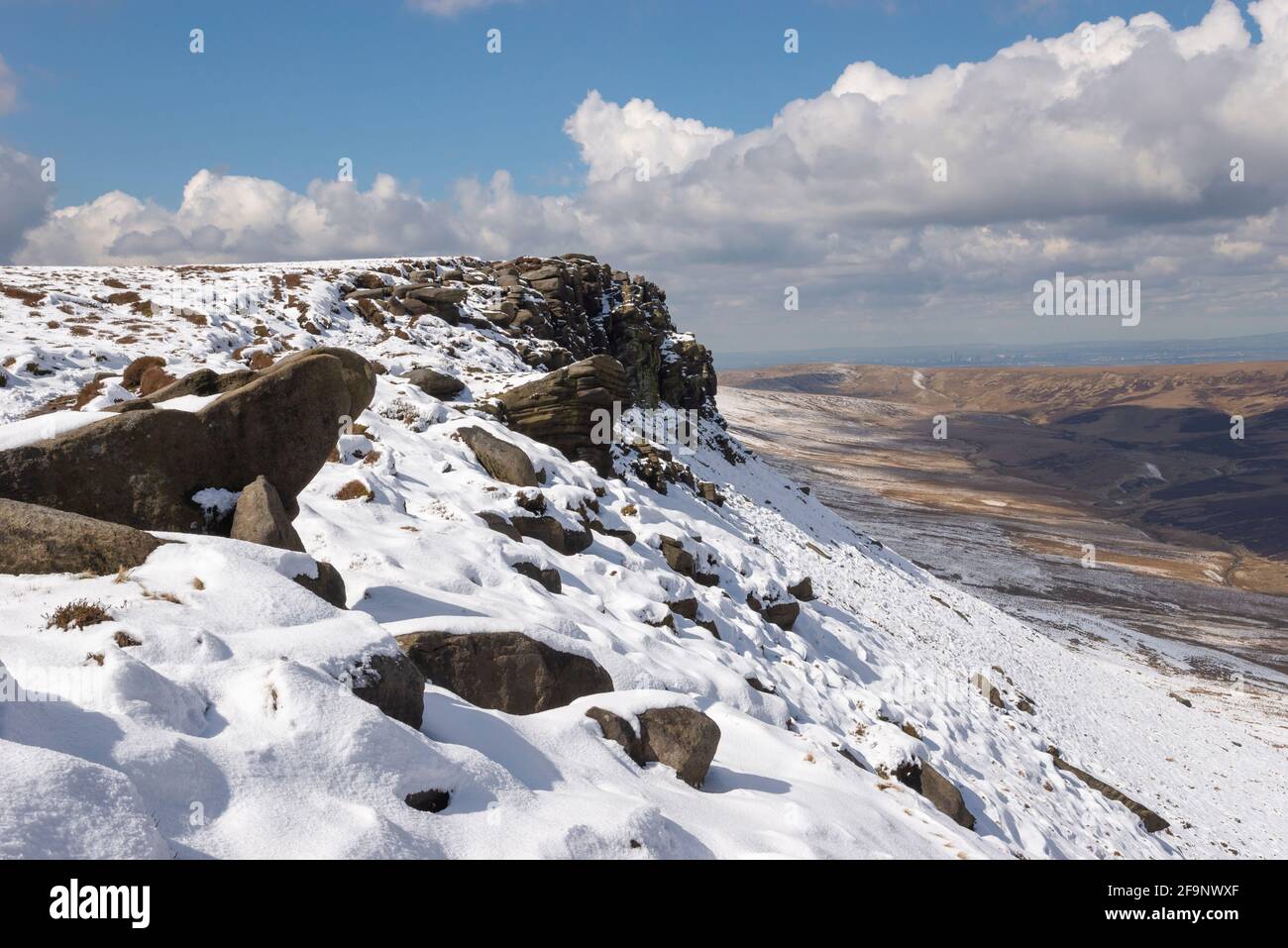 Spectacular view from the northern edge of Kinder Scout, Peak District with Manchester in the far distance. Remnants of late snow on the edge. Stock Photo