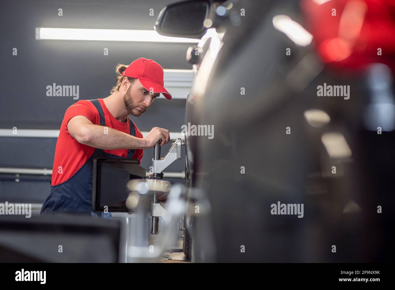 Young man working near car wheel in garage Stock Photo - Alamy