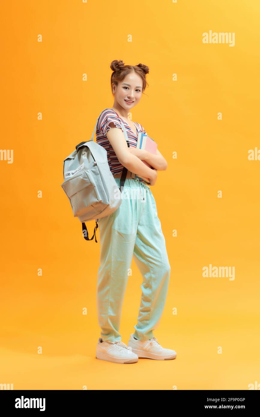Full length portrait of a cute smiling girl holding books isolated on ...