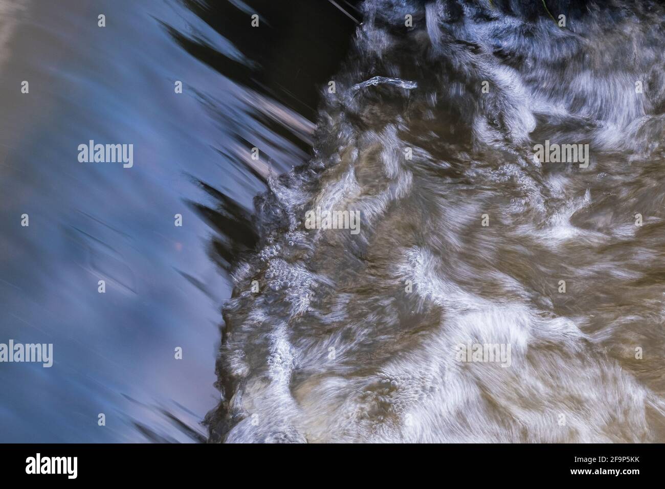 Water swirling at the bottom of a small cascade in a stream. Stock Photo