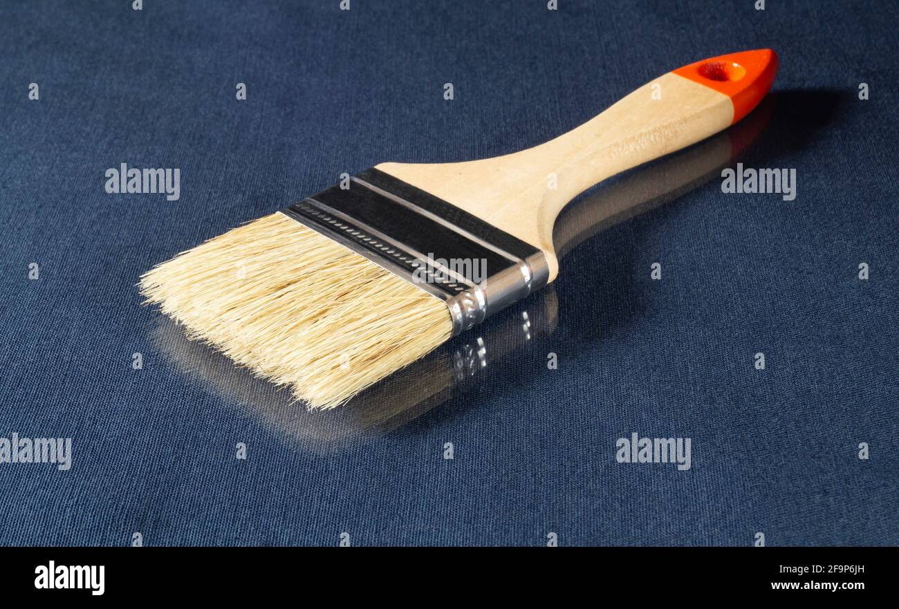 Paint brush with wooden handle on the table. Tools on a blue background with reflection Stock Photo