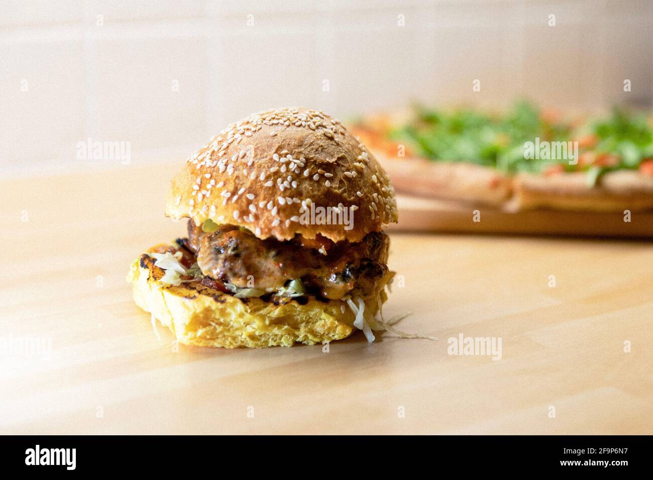 A Mexican beef burger with a pizza in the background Stock Photo