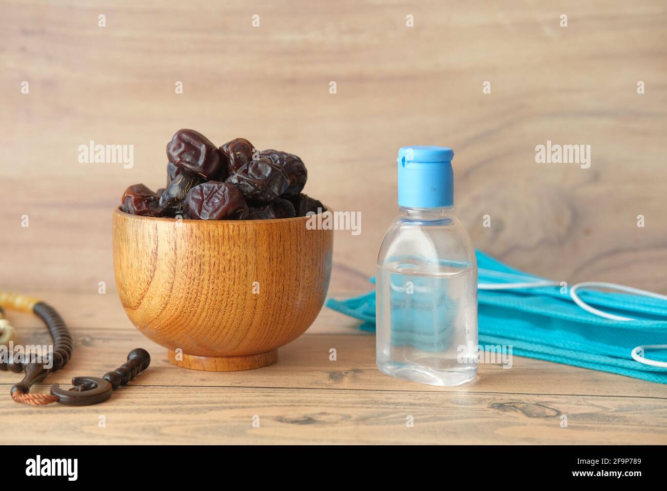 fresh date fruit in a bowl , prayer rosary , hand sanitizer and mask on table  Stock Photo