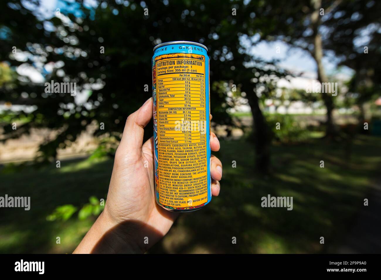 A hand holding a Monster Energy can drink showing nutrition information content. Stock Photo