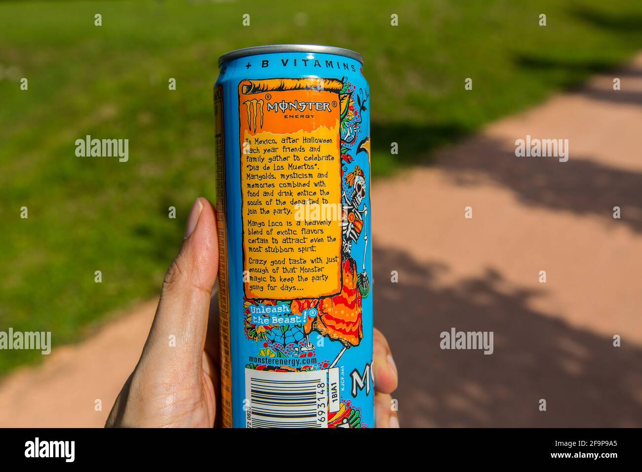 A hand holding a Monster Energy can drink, the panel explains the concept or idea of the drink. Stock Photo