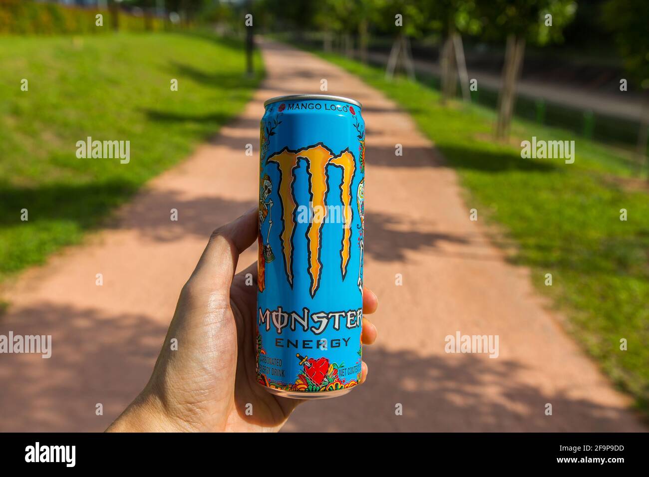Left hand holding Monster Energy drink in outdoor. Stock Photo