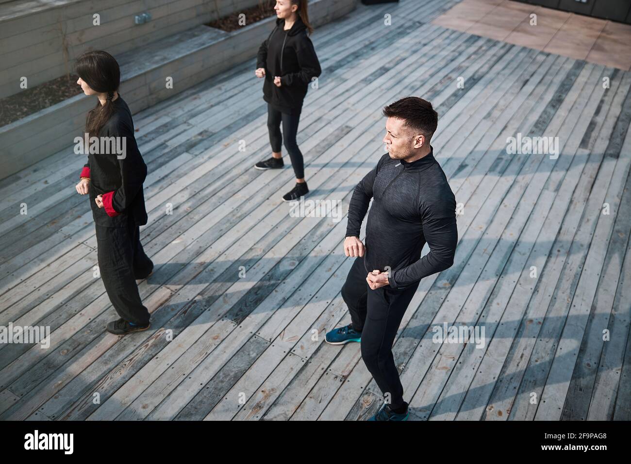 Male with tense muscles standing next to tai chi group Stock Photo