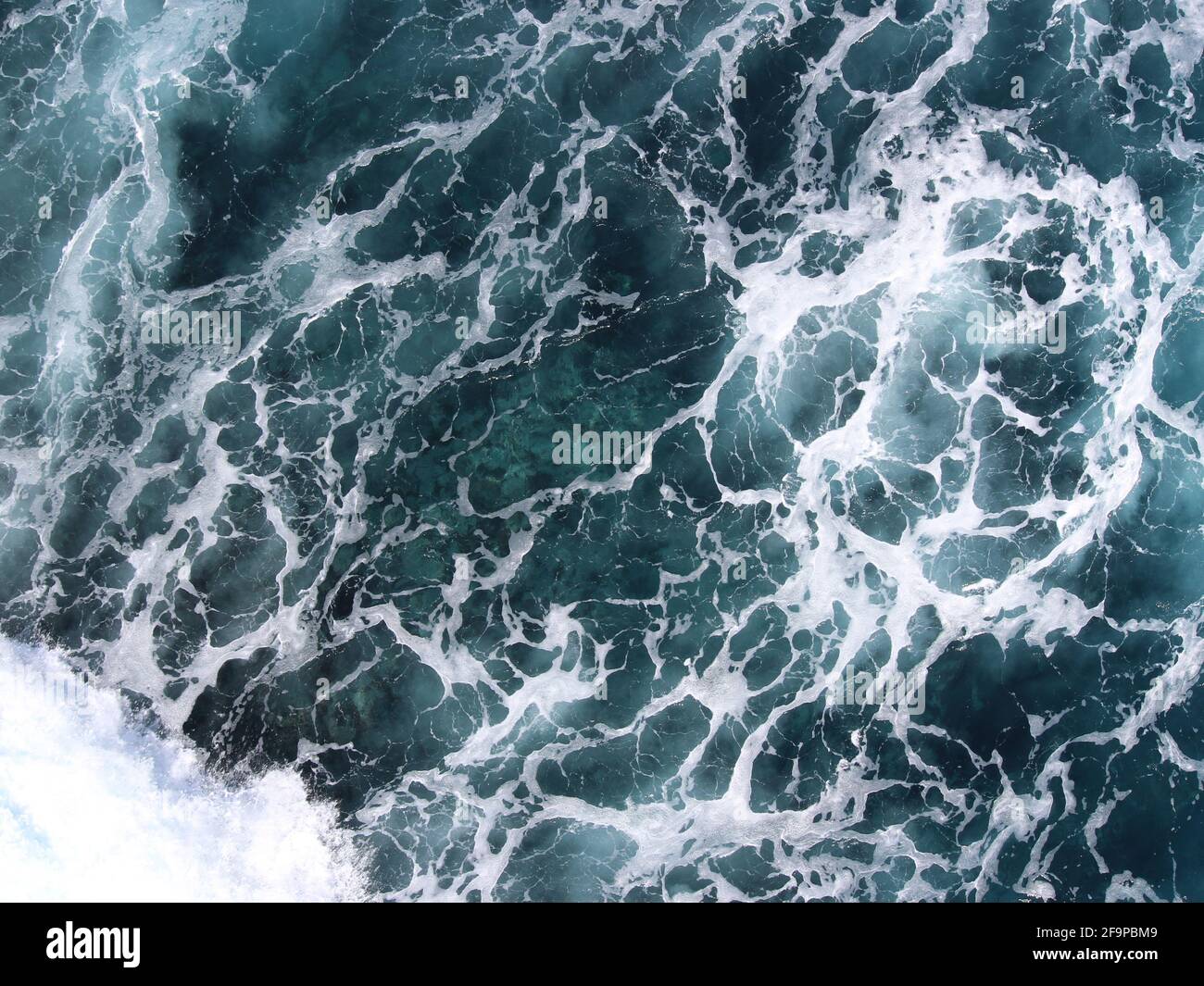 Foamy ocean reveals rock beneath Stock Photo Alamy