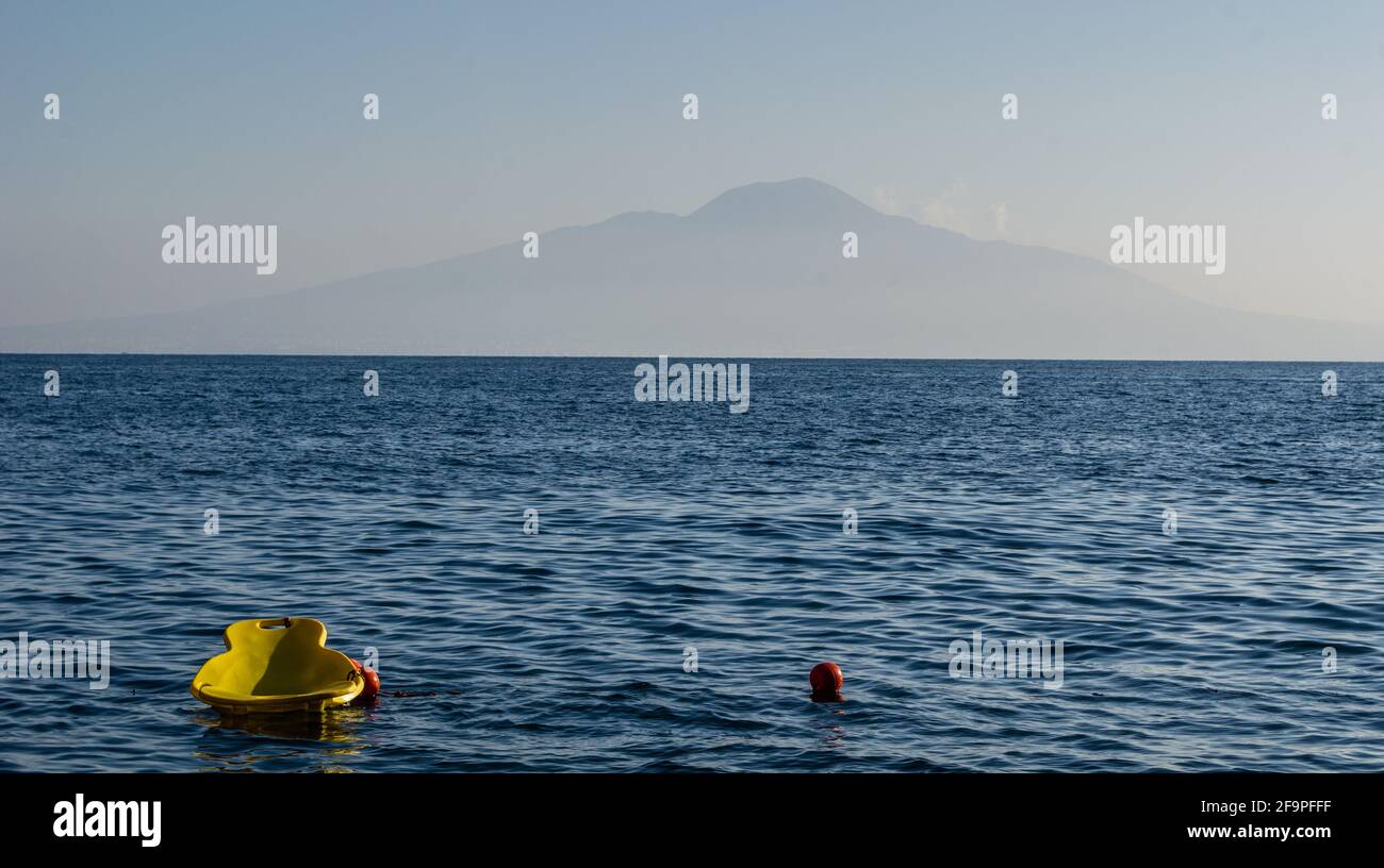 small yellow floating chair with mount vesuvius behind it. Stock Photo