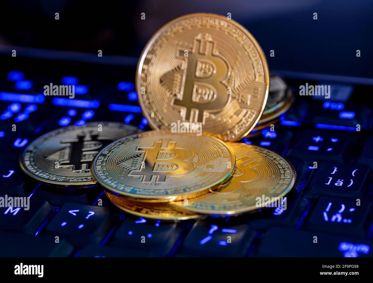 Bitcoin, new Virtual money concept. Gold bitcoins with blue lighting computer keyboard background. Golden coin with icon letter B. Mining or blockchai Stock Photo