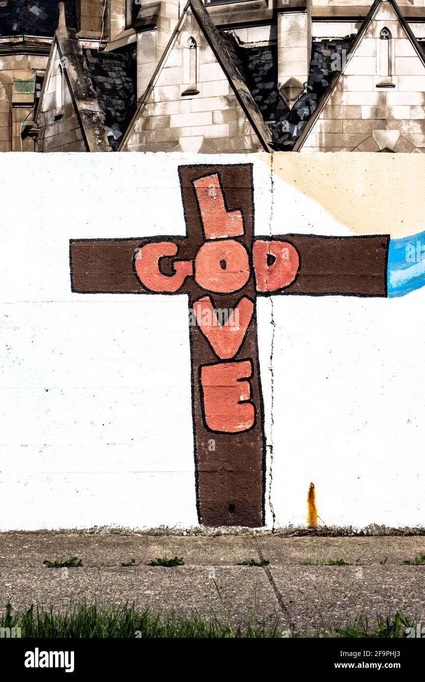Words on a wall saying Love God - these letters are inside a brown cross  and the wall is white. Stock Photo