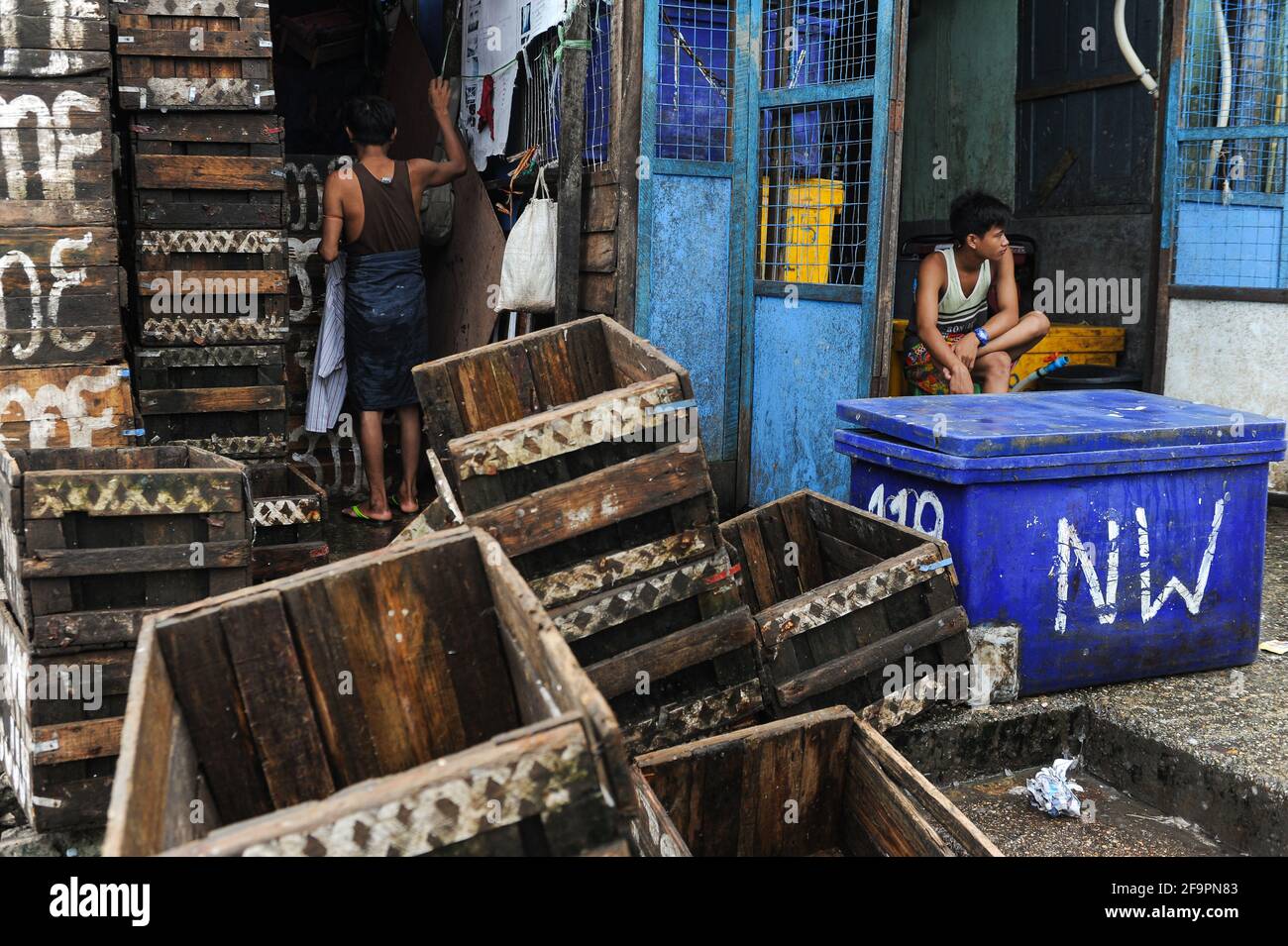 28.06.2014, Yangon, , Myanmar - Workers surrounded by empty wooden crates and refrigerated boxes at the traditional Baho San Pya fish market, a wholes Stock Photo