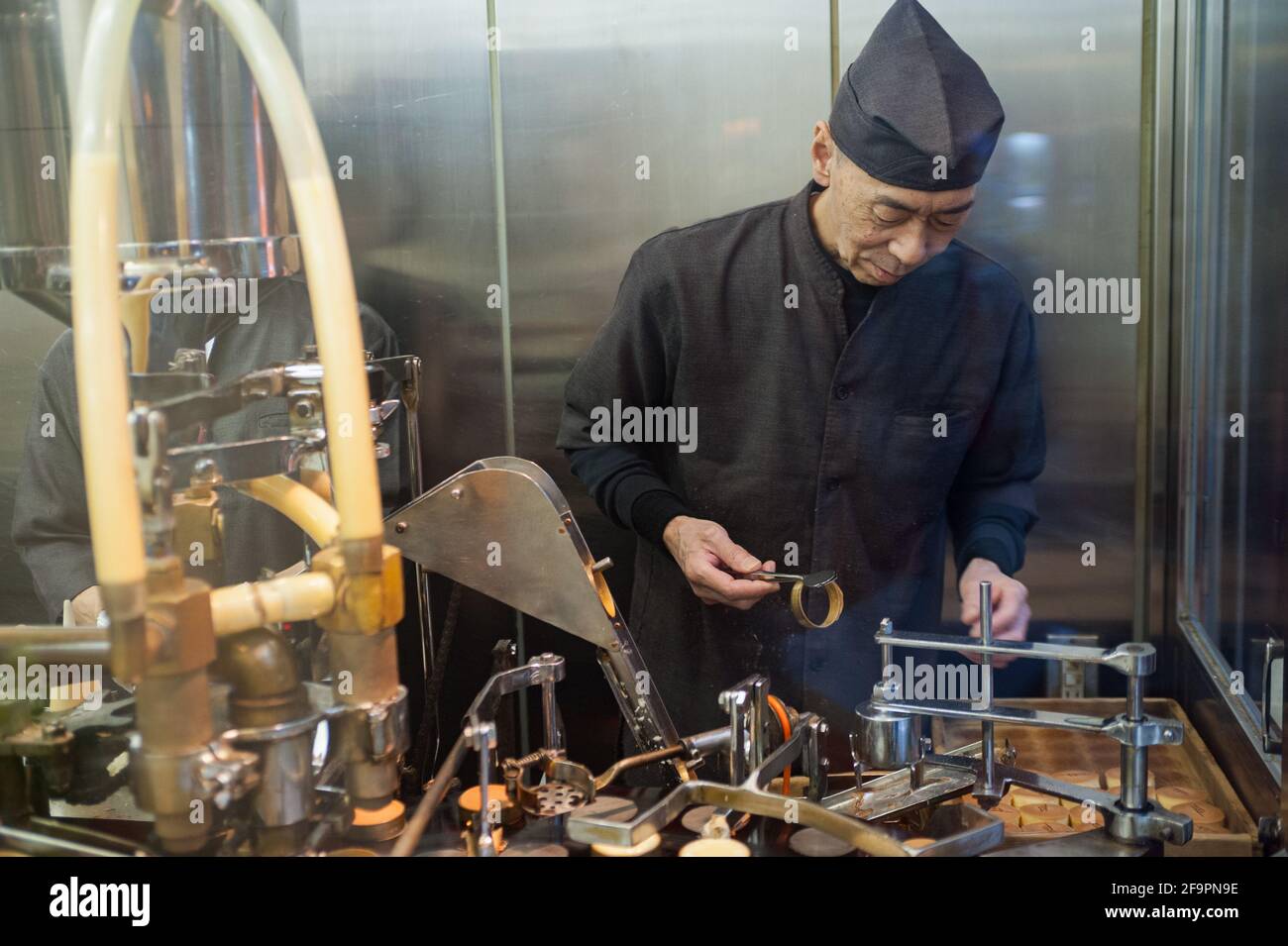 25.12.2017, Kyoto, Kansai, Japan - A pastry chef stands behind the shop window of a pastry shop - patisserie and prepares fresh biscuits with the help Stock Photo