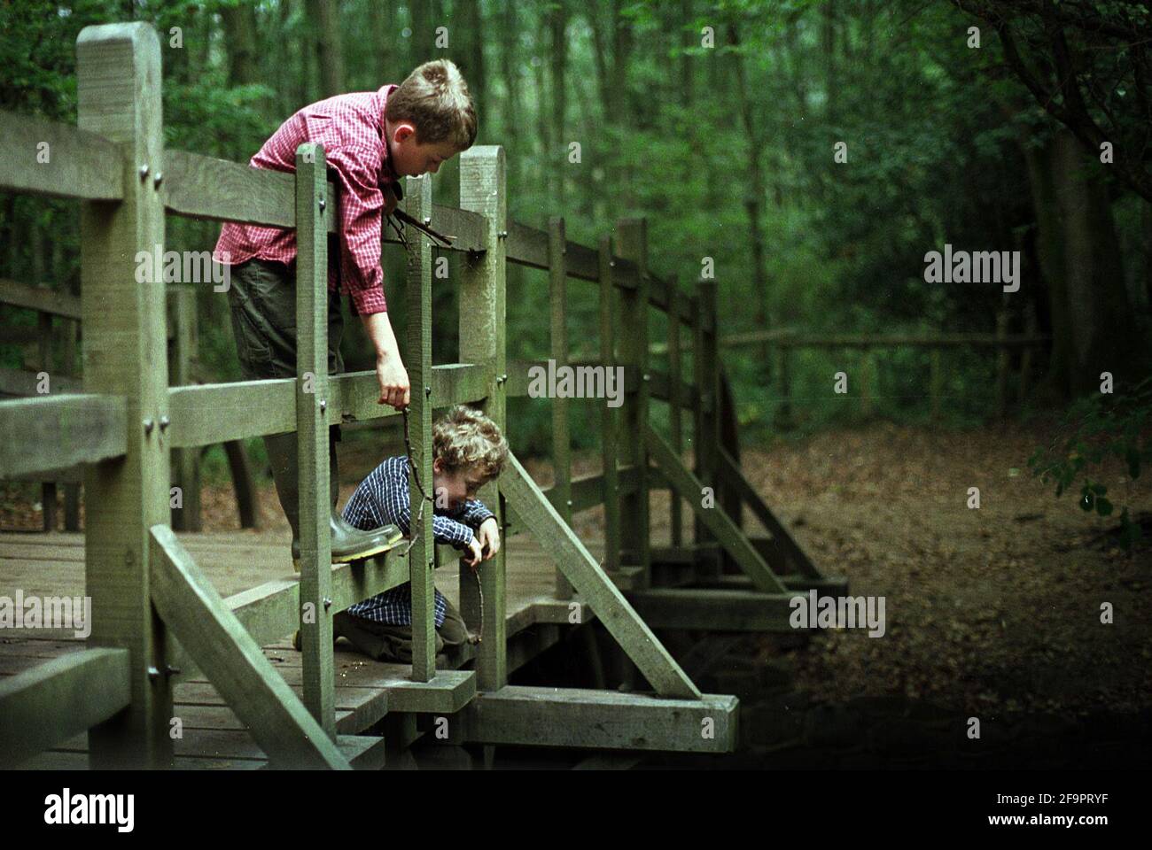 ON ITS THE 75 ANNIVERSARY ,TWO CHILDREN PLAY POOH STICKS ON POOH BRIDGE IN THE ASHDOWN FOREST. 14/10/01 PILSTON Stock Photo