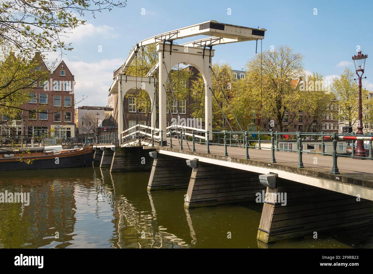 Typical double wooden drawbridge spans a canal in Amsterdam. Stock Photo