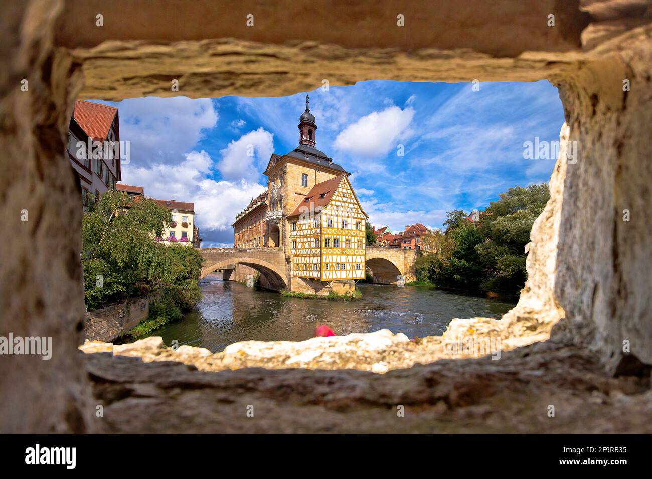 Bamberg. Scenic view of Old Town Hall of Bamberg (Altes Rathaus) with two bridges over the Regnitz river view through stone window, Bavaria region of Stock Photo