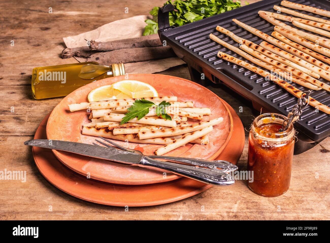 Grilled scorzonera with sauce. Cutlery, rustic ceramic plates, grill