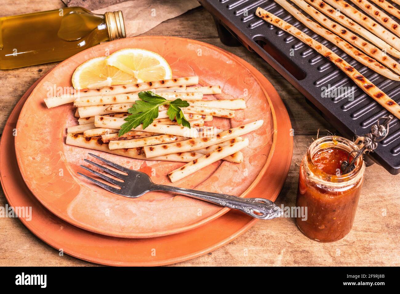 Grilled scorzonera with sauce. Cutlery, rustic ceramic plates, grill