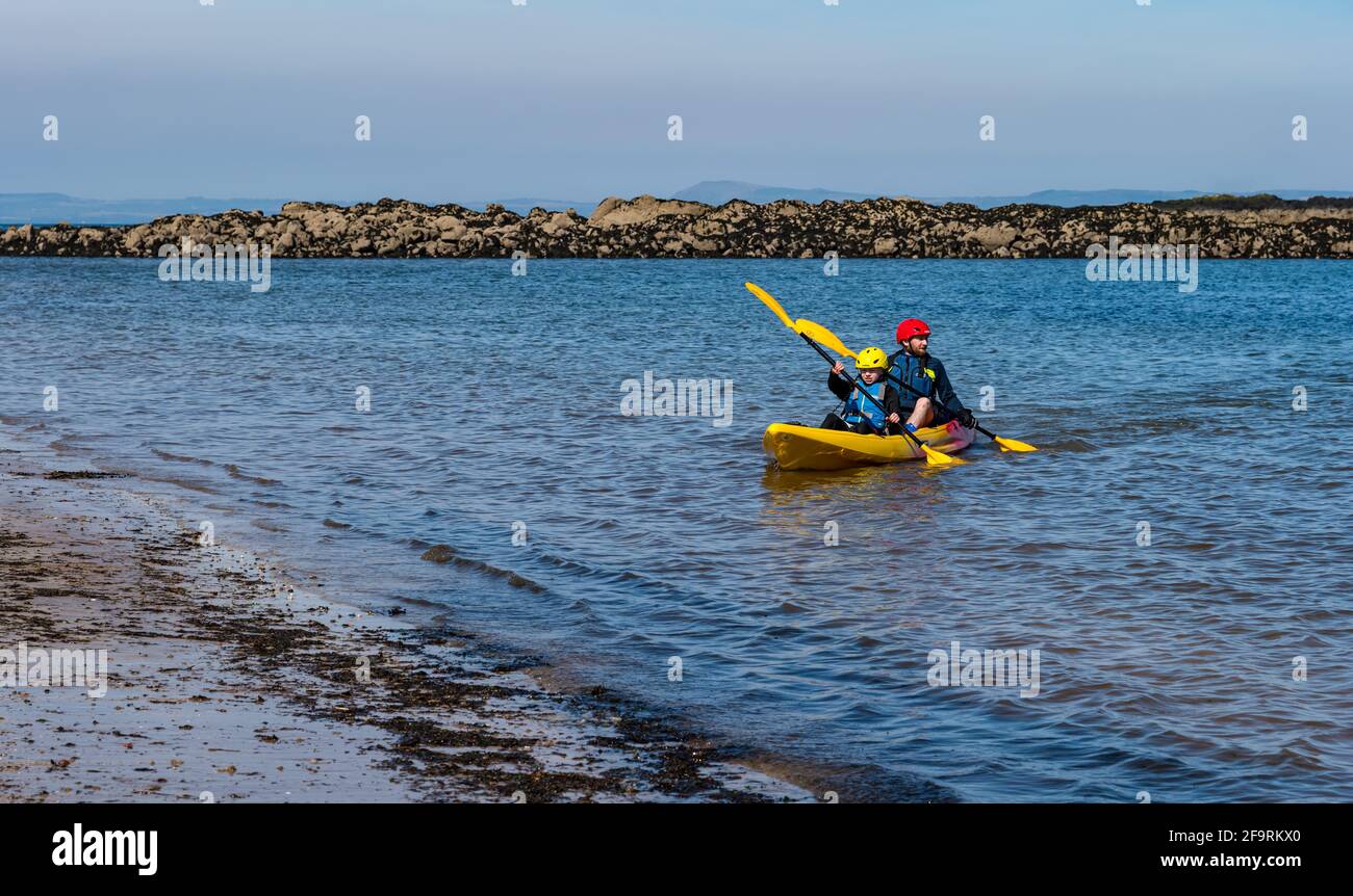 Man and boy paddling in kayak in Firth of Forth at West Bay beach
