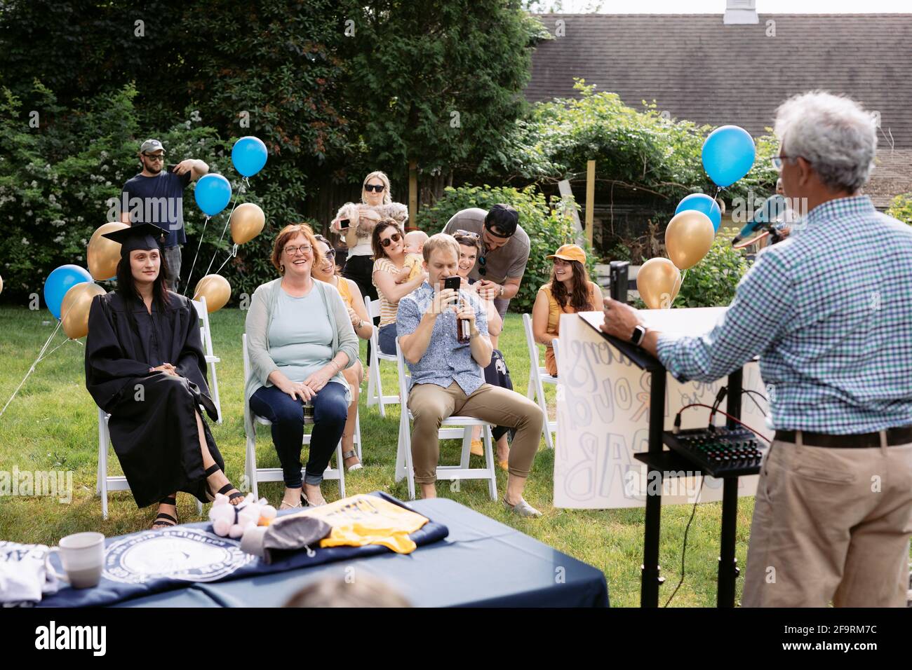 Father giving speech at daughter's college graduation in backyard Stock Photo