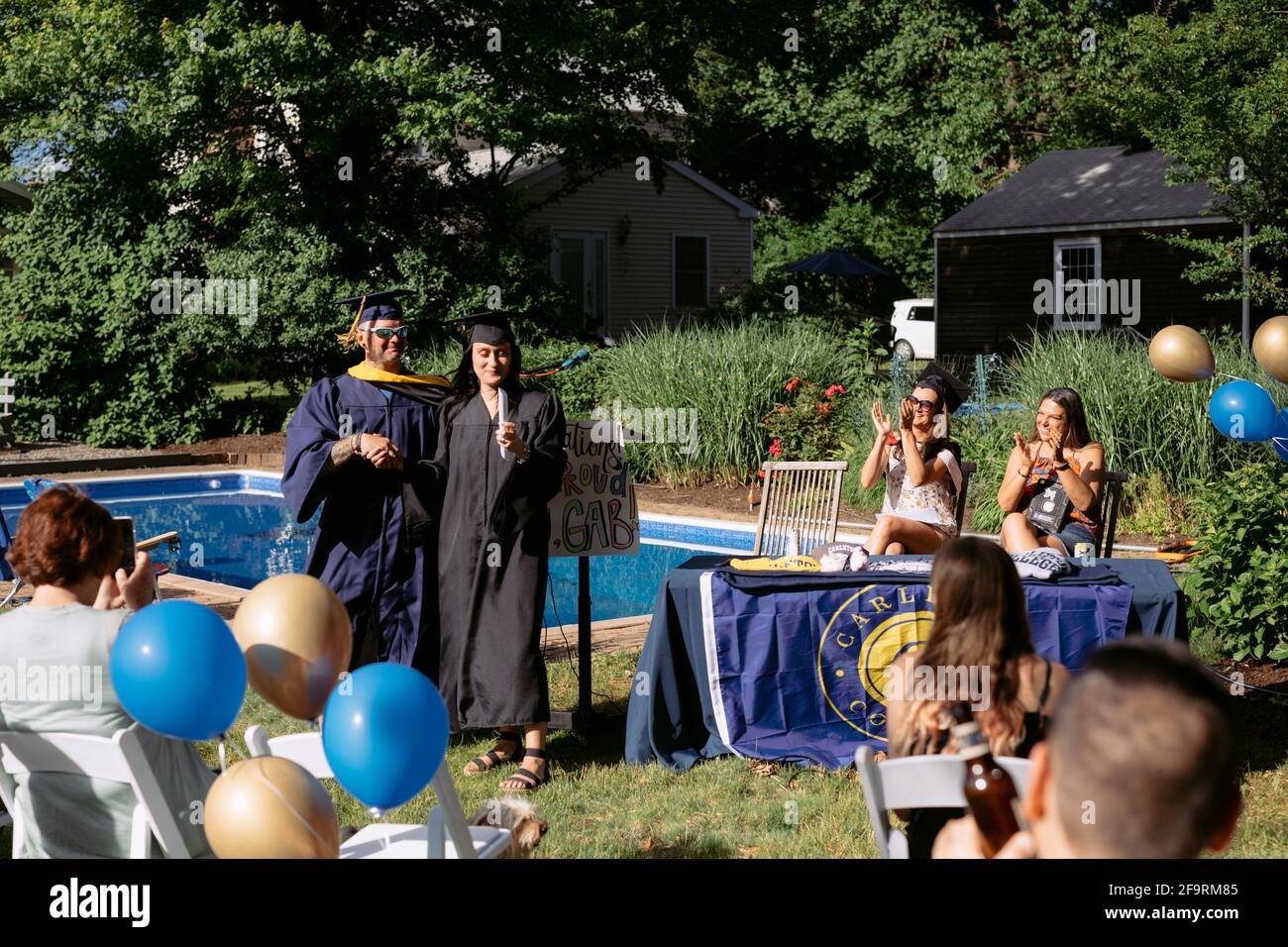 Young woman receives handmade diploma at backyard college graduation Stock Photo