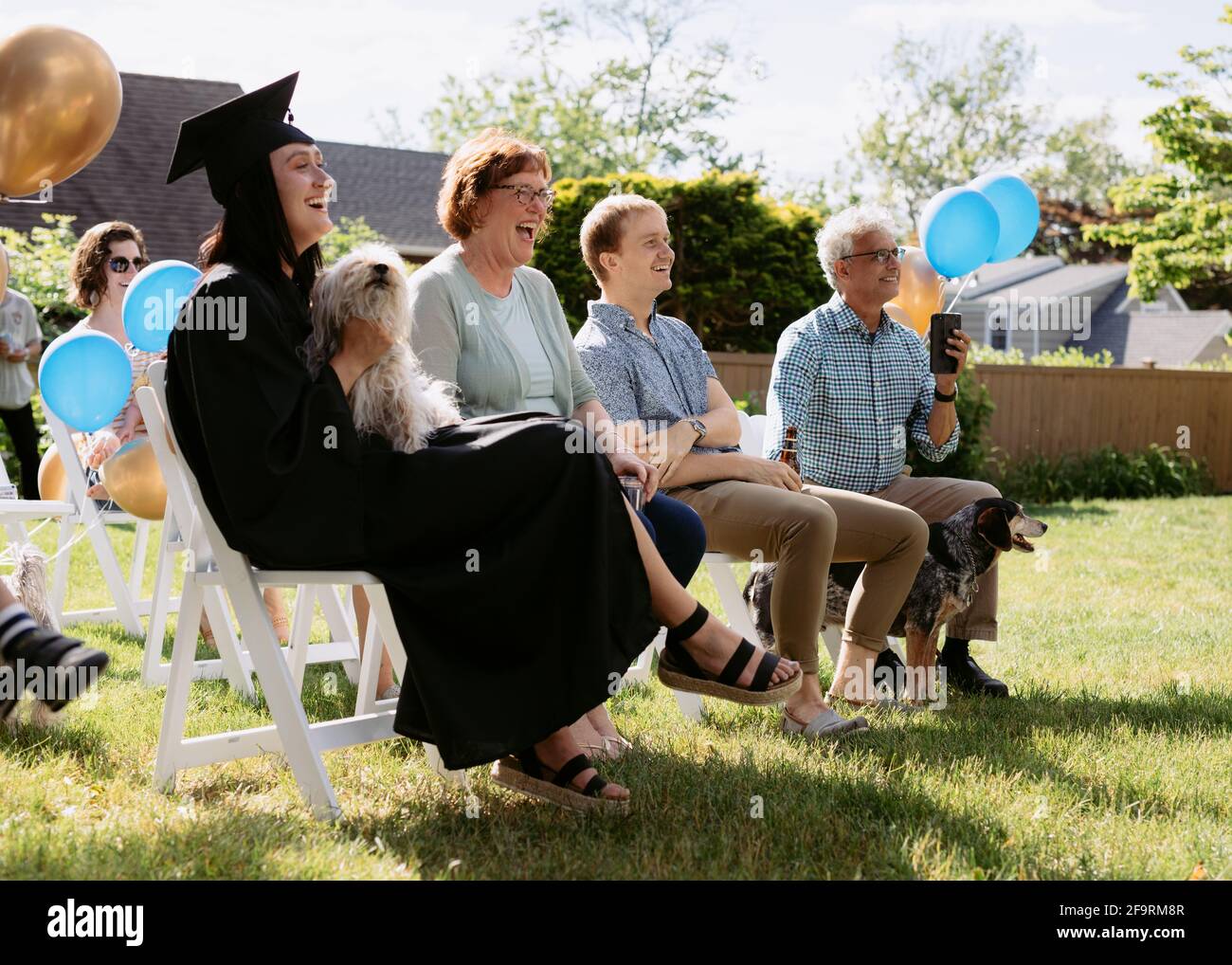 Family laughing and smiling at backyard covid graduation ceremony Stock Photo