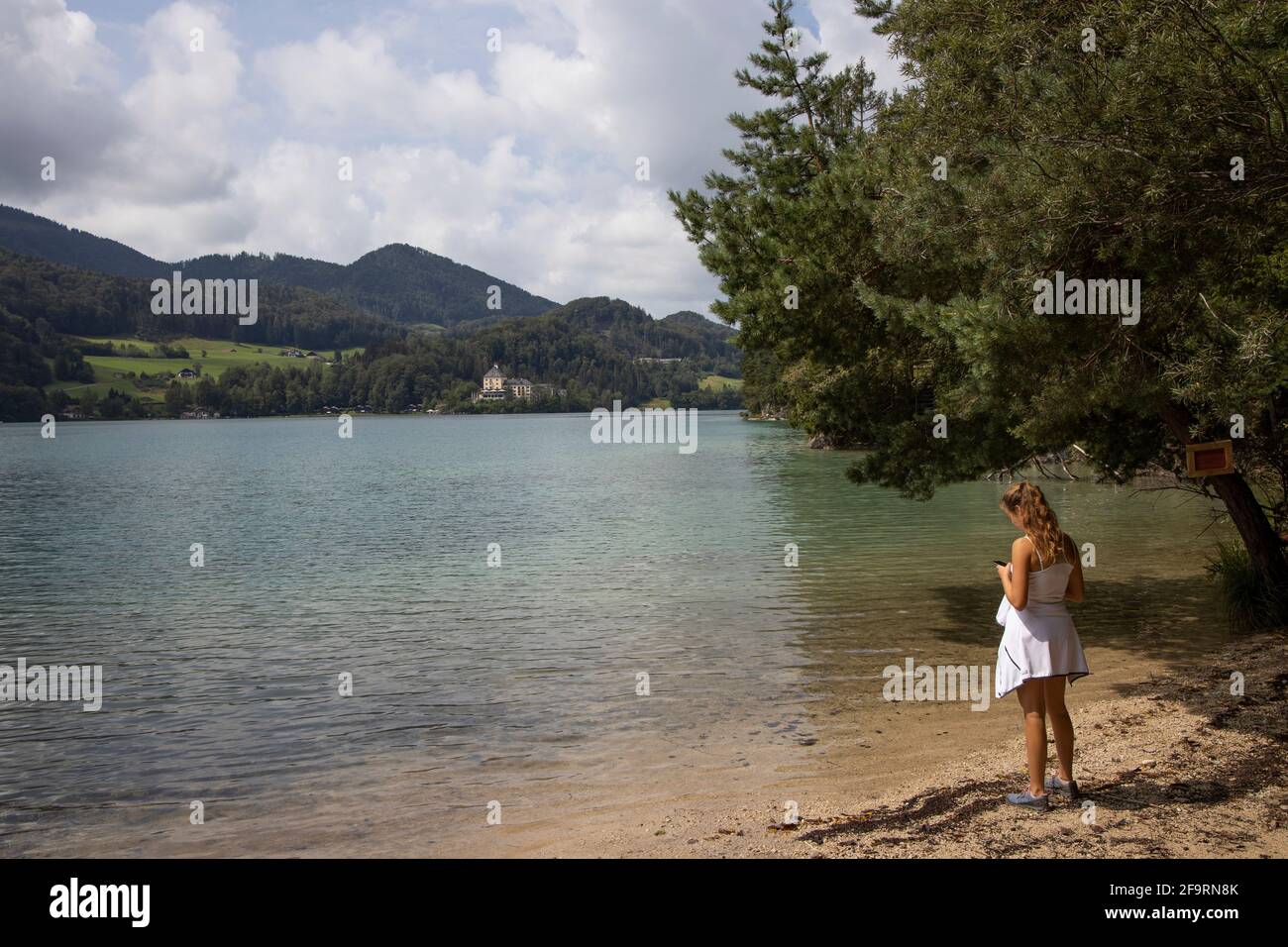 Young female hiker standing on the shore of Lake Fuschl  in Fuschl,Salzburg,Salzkammergut,Austria,Europe. Stock Photo