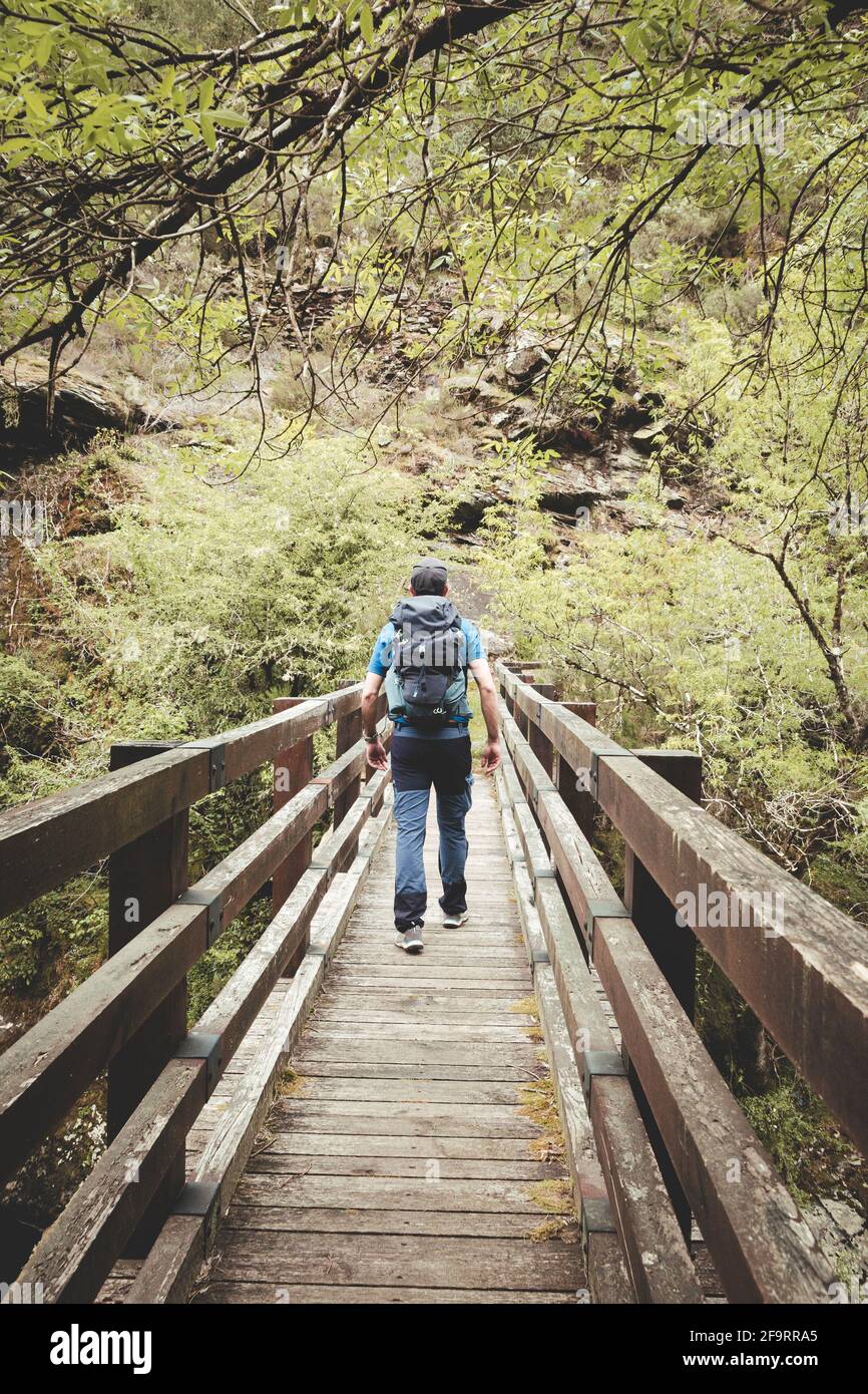 Man with backpack and cap crossing a bridge Stock Photo Alamy