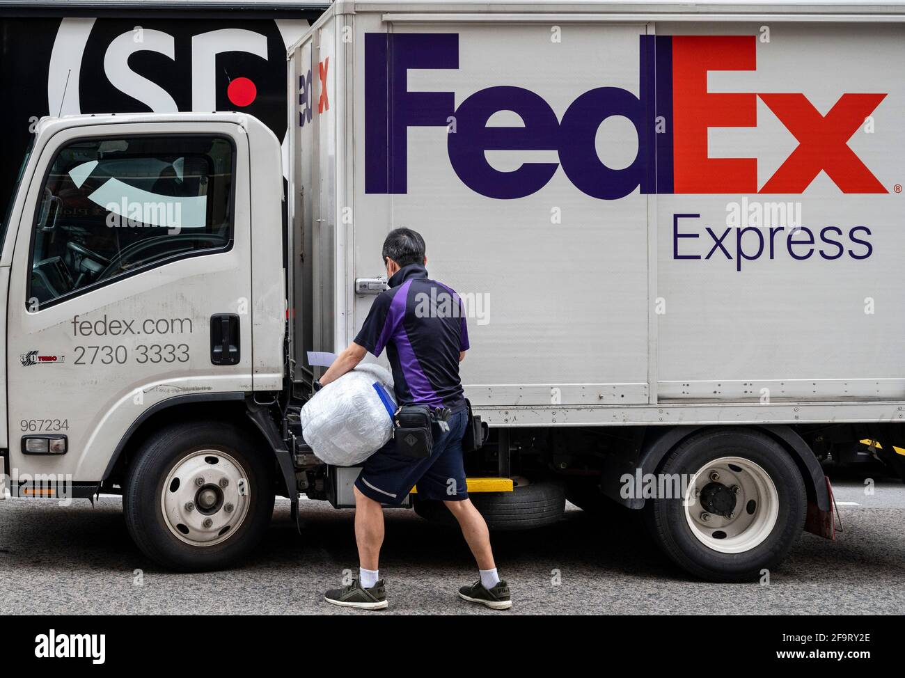 A worker of the American FedEx Express delivery seen getting in the truck  as Chinese multinational delivery services and logistics company SF Express  trucks are stationed in the street in Hong Kong. (