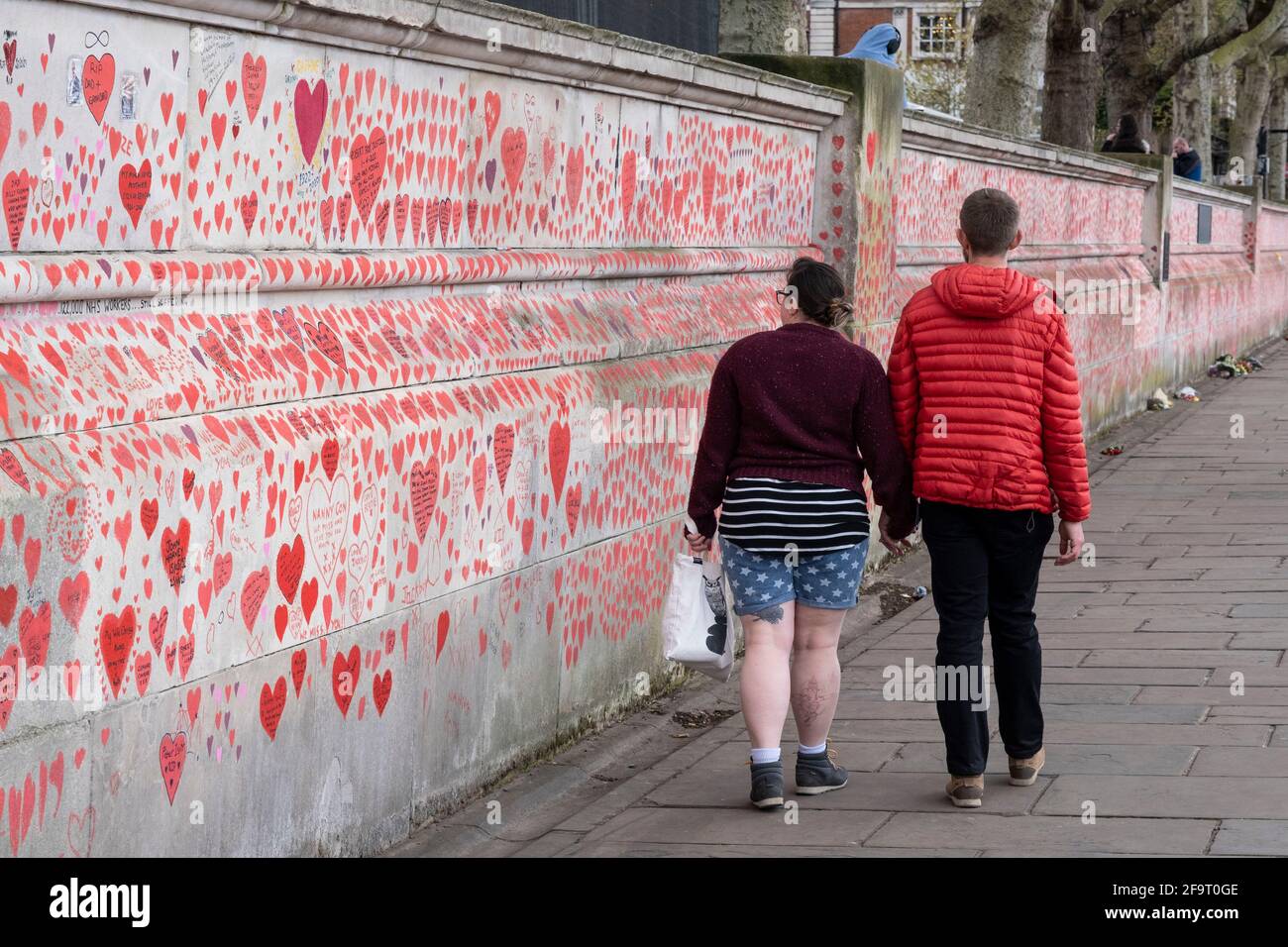 Red hearts painted in memory of people who have died of Covid-19 during the coronavirus pandemic at the National Covid Memorial Wall on 13th April 2021 in London, United Kingdom. The wall is  a place for people to come to reflect or to write messages or the names of lost loved ones. The wall represents a tribute to the approximately 150,000 British victims pandemic. Stock Photo