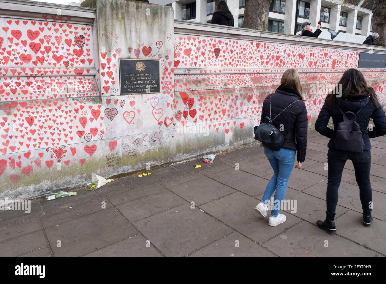 Red hearts painted in memory of people who have died of Covid-19 during the coronavirus pandemic at the National Covid Memorial Wall on 13th April 2021 in London, United Kingdom. The wall is  a place for people to come to reflect or to write messages or the names of lost loved ones. The wall represents a tribute to the approximately 150,000 British victims pandemic. Stock Photo