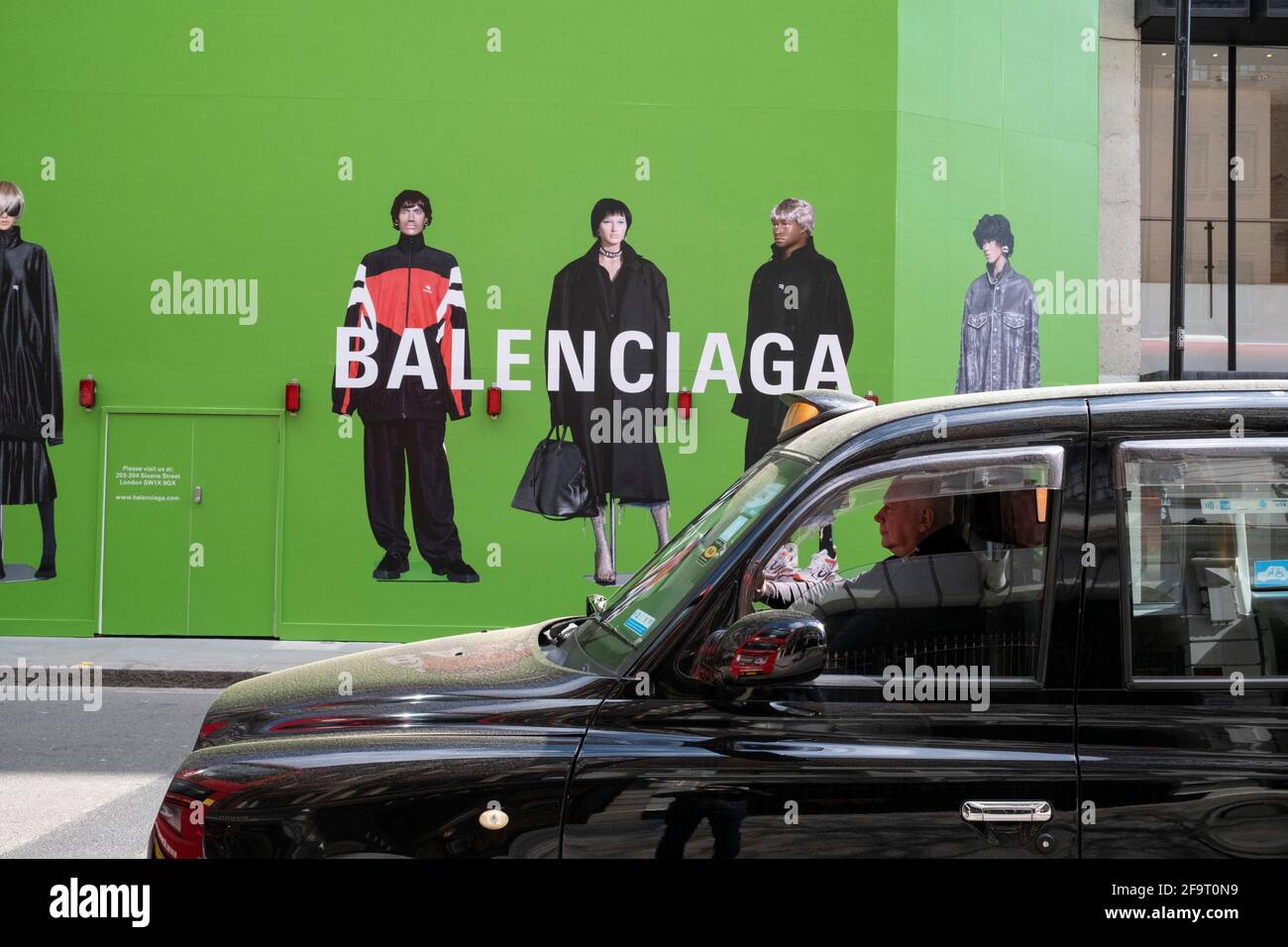 Large scale action figures wearing fashionable clothing against a huge  green hoarding which covers the Balenciaga store during a refit in the  upmarket area of Knightsbridge on 14th April 2021 in London,