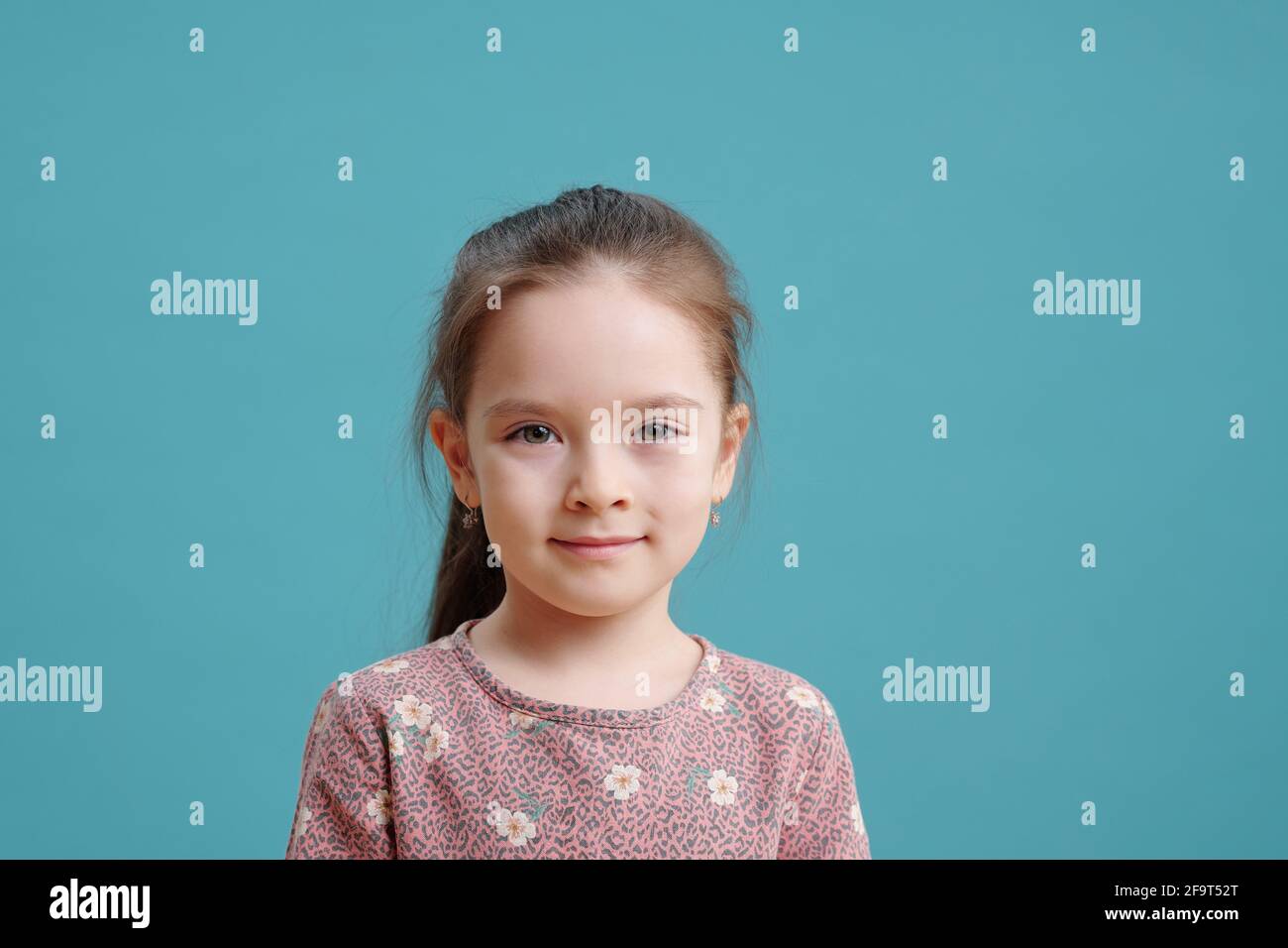 Portrait of cute little girl looking at camera isolated on blue ...
