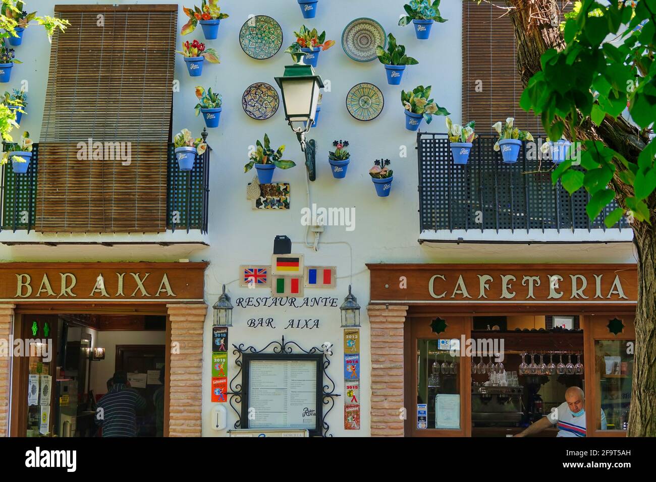 Facade with colorful ceramic decorations of a traditional cafeteria in the Albaicín neighborhood of Granada (Spain) with the waiter at the entrance Stock Photo