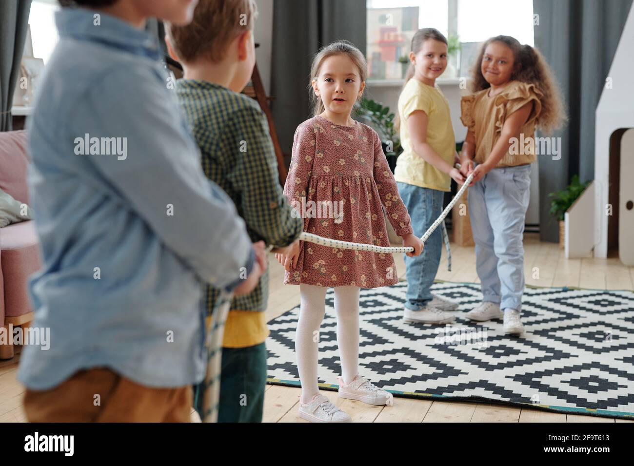 Group of children pulling the rope during game in the living room at domestic party Stock Photo