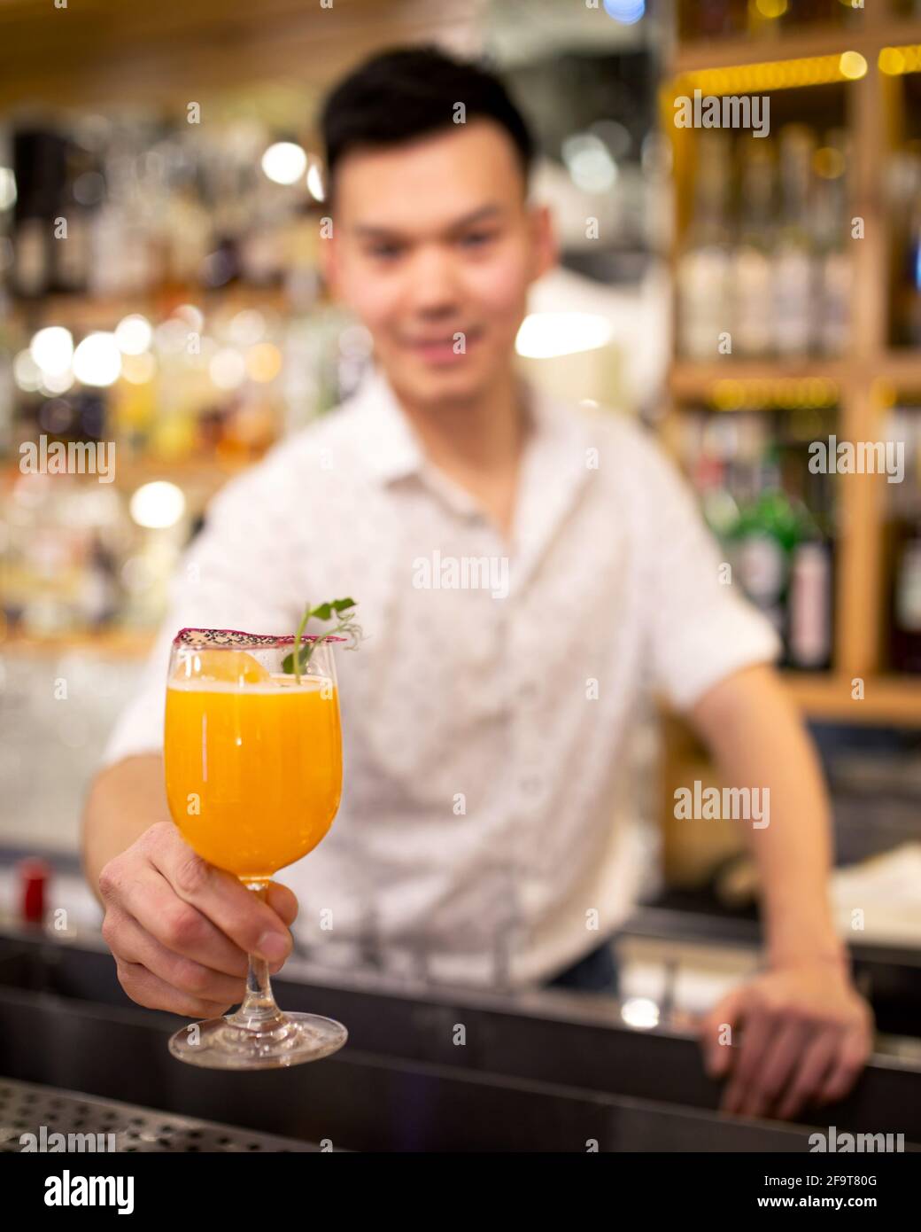 Bartender on the bar stretches out an orange cocktail Stock Photo Alamy