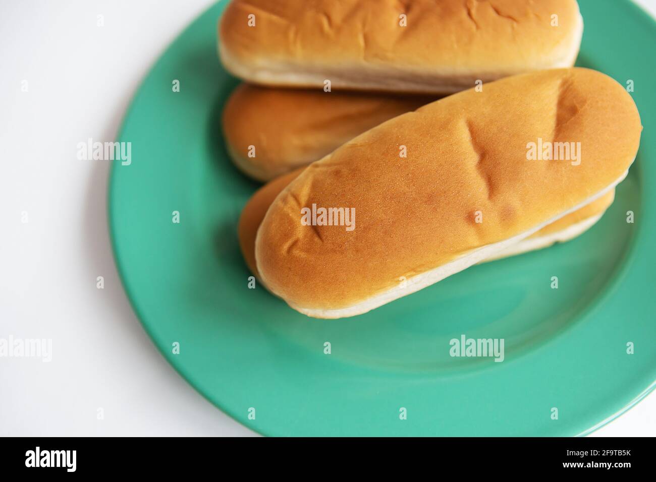 Fresh hot dog buns which lie on a green plate. Top view, closeup Stock