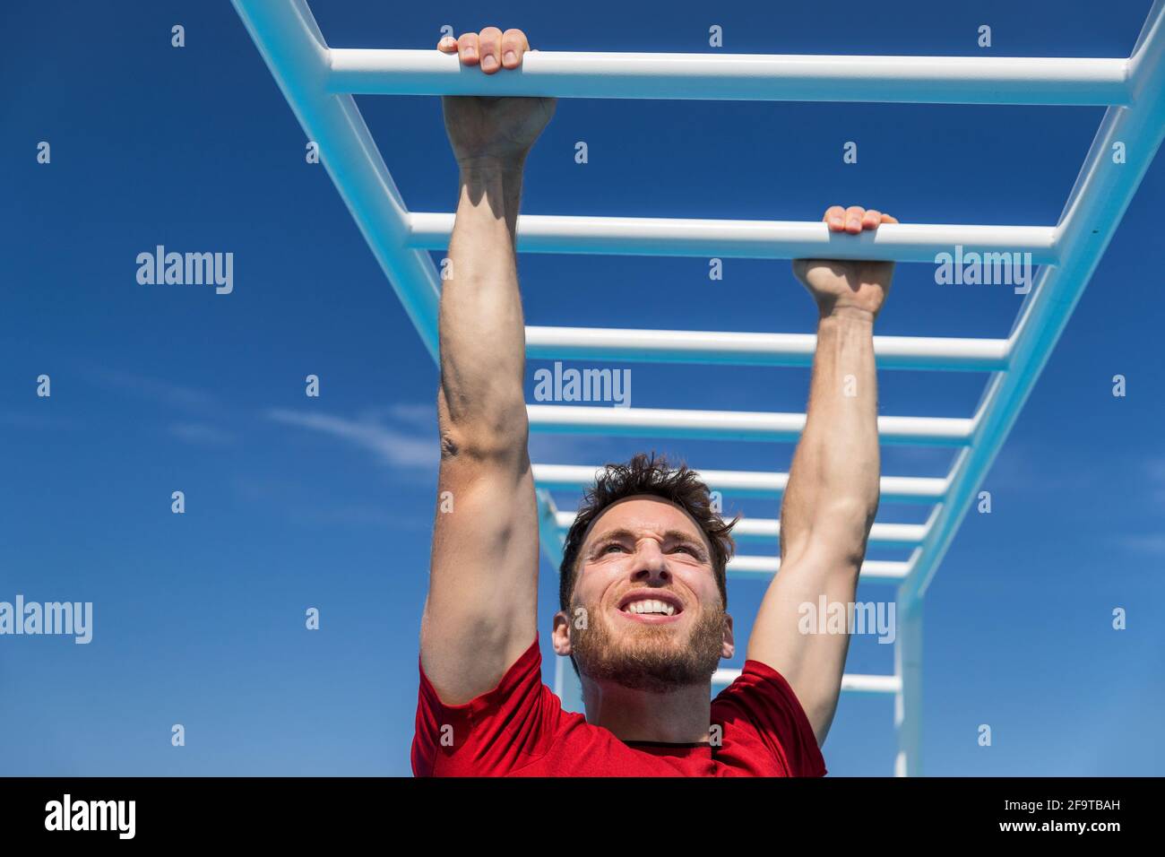 Fitness monkey bars man training arms muscles on jungle gym outdoors in summer. Athlete working out gripping climbing on ladder equipment at sport Stock Photo