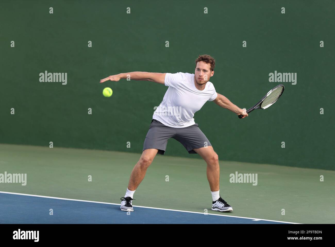 Professional tennis player athlete man hitting forehand ball on hard court playing tennis match. Sport game fitness lifestyle person living an active Stock Photo