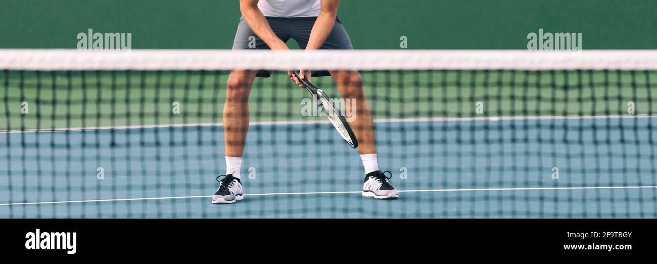Tennis ready position male athlete player waiting for volley serve at net on blue hard court banner crop. Closeup of feet and legs standing waiting Stock Photo