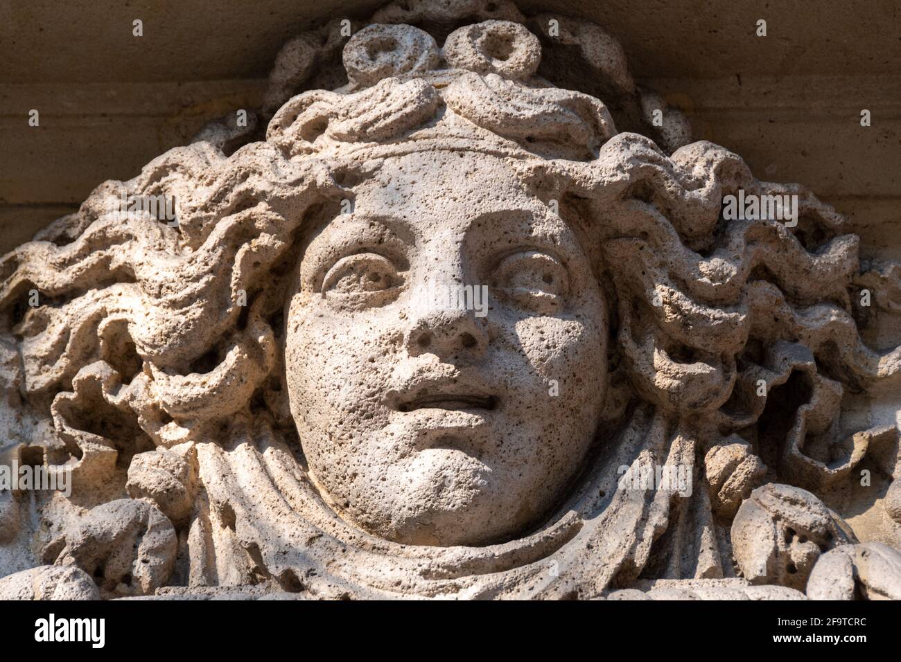 Woman's face carved in stone, probably an allegory of fortune, facade ornament of an old building in Paris, France Stock Photo