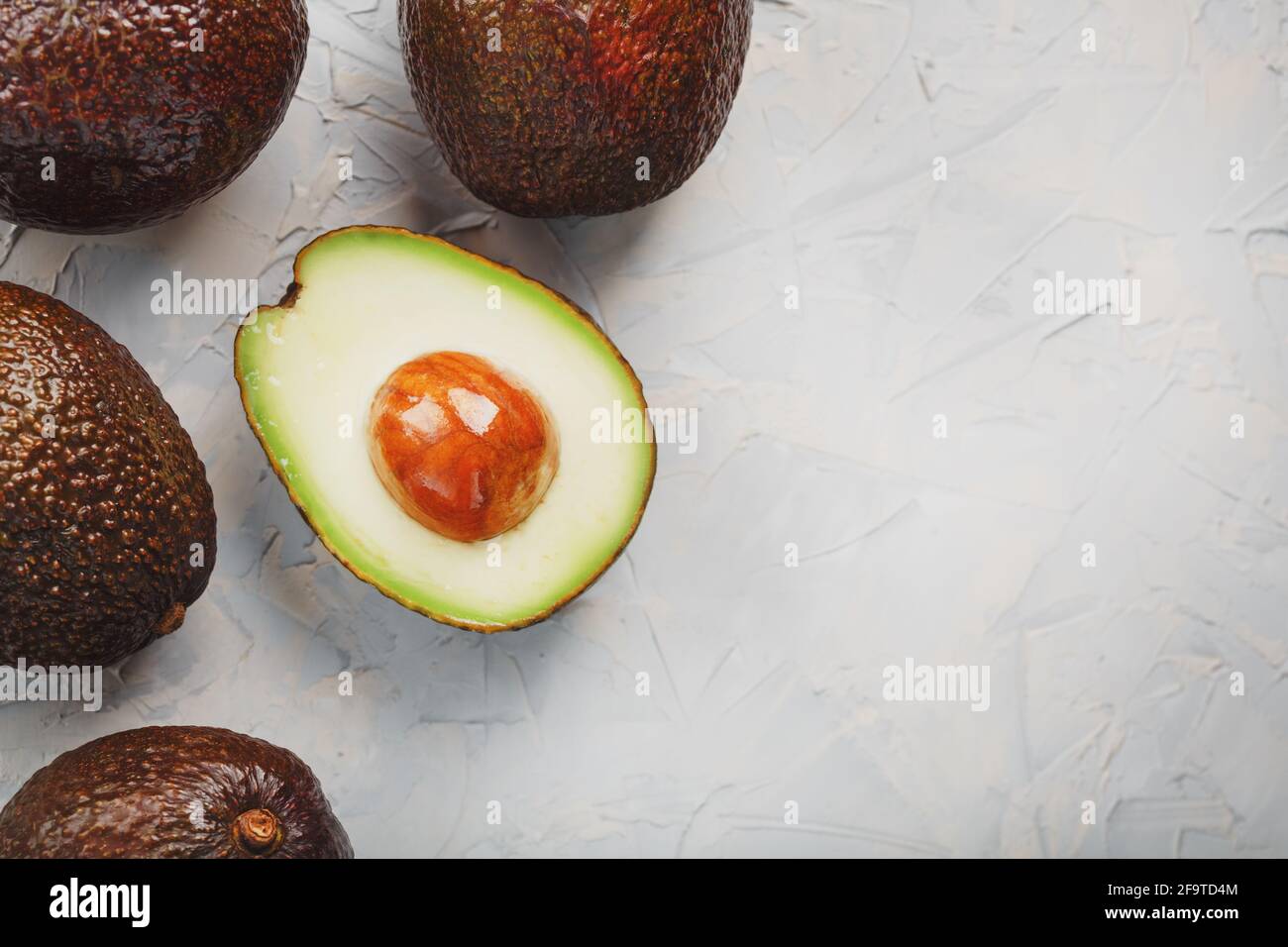 Sliced and whole organic Hass avocado on a gray background. A source of