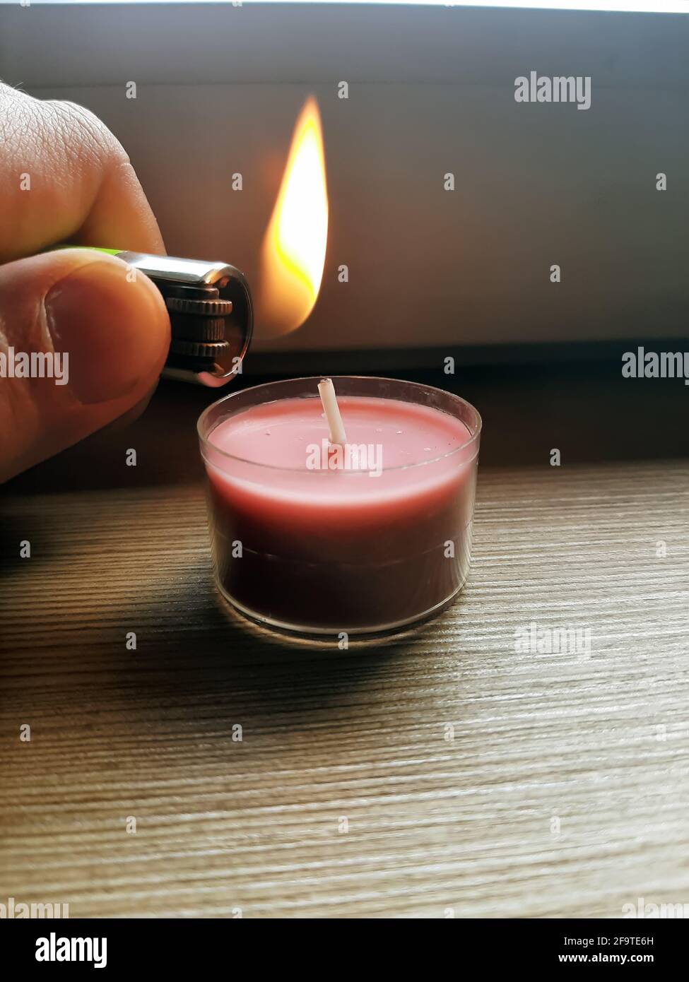 Lighting candle with a lighter. Hand holding lighter with flame. Stock Photo