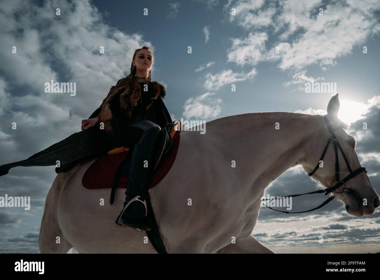 Young viking woman with red hairs ride a horse. Dramatic light. Role-playing game Stock Photo