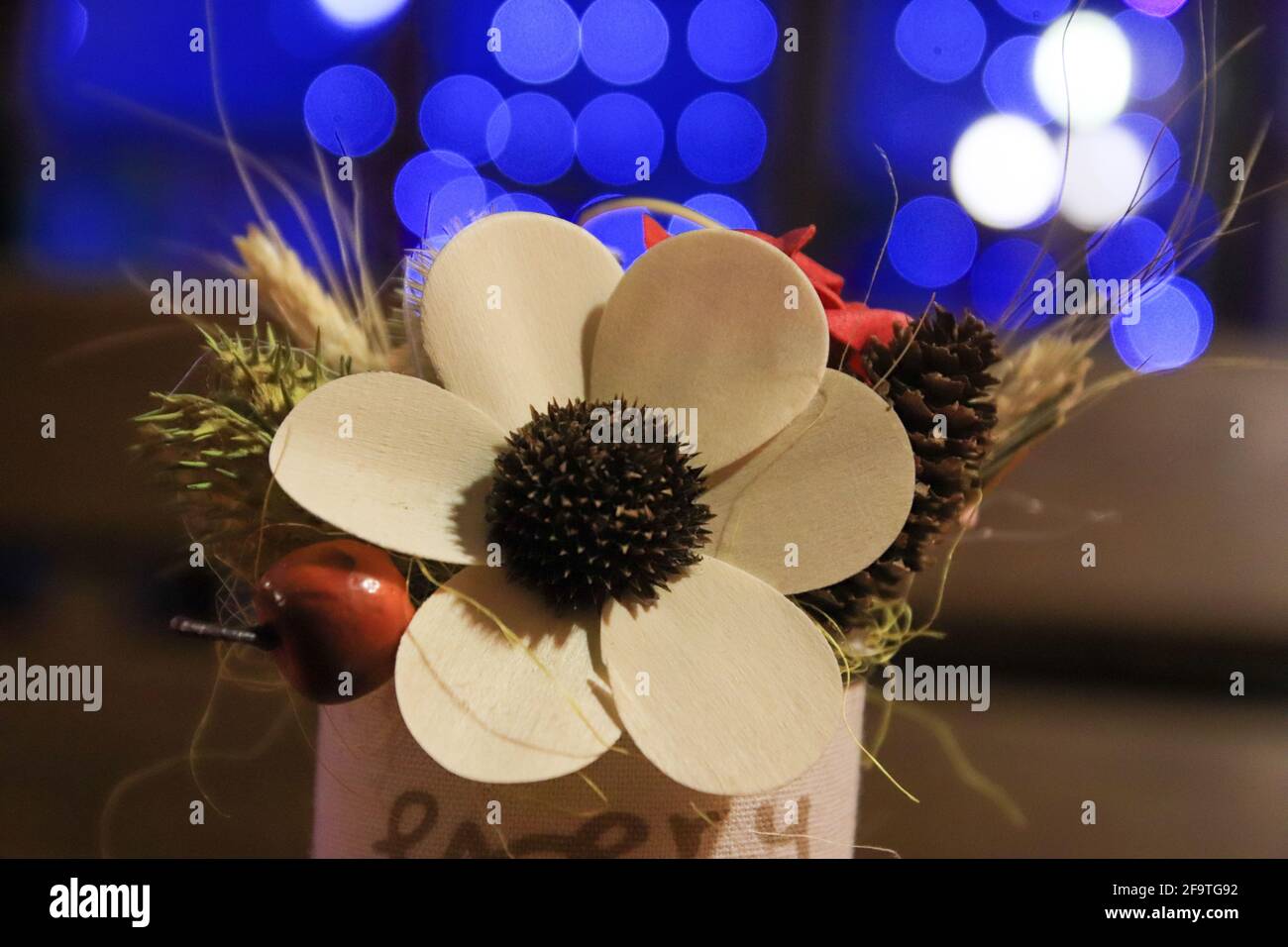 Artificial flower on table with bokeh blue lights on background Stock Photo