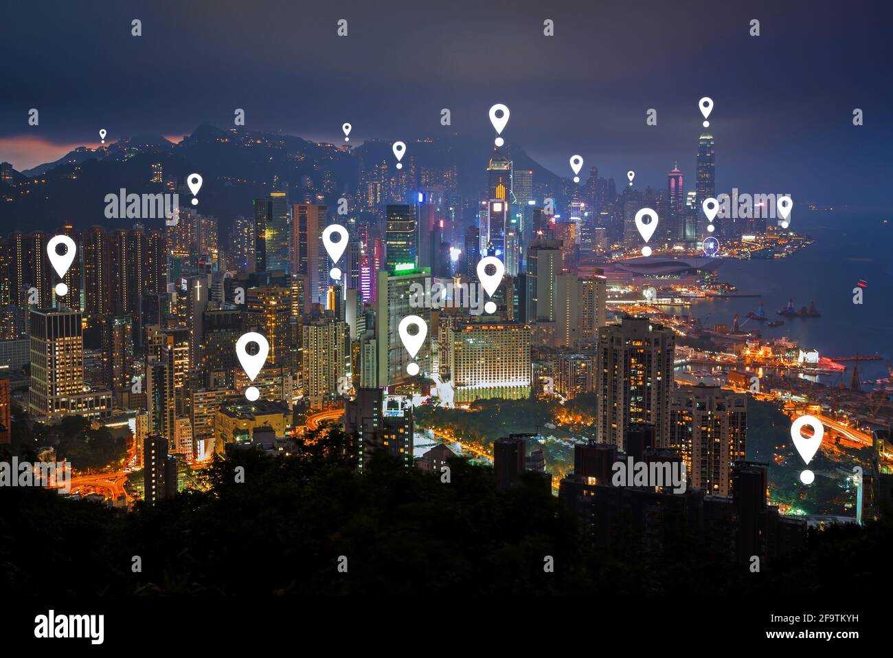 Map pin icons on Hong Kong's cityscape at night. Lit skyscrapers on Hong Kong Island in Hong Kong, China, viewed from above at dusk. Stock Photo