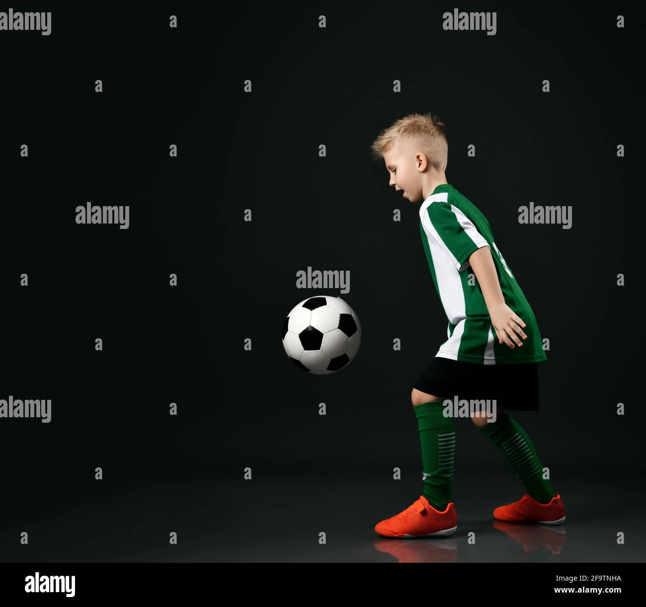 Active sporty schoolboy in soccer player uniform plays with ball, going to kick and scoring a goal Stock Photo