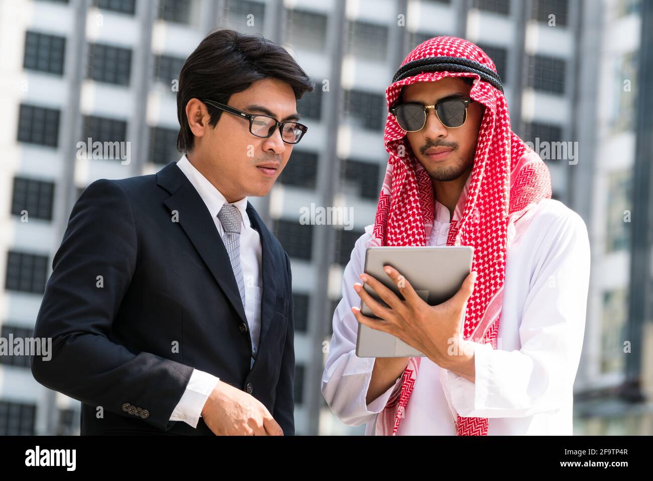 Arab man and businessman discuss content in tablet computer. Multicultural international oversea business meeting. Stock Photo