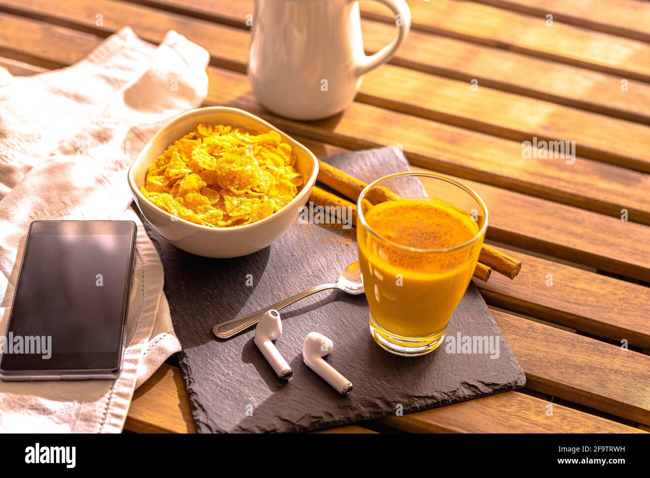 selective focus Breakfast on wooden table with mobile phone headset with golden milk food with turmeric and cinnamon accompanied by cereals Indian foo Stock Photo
