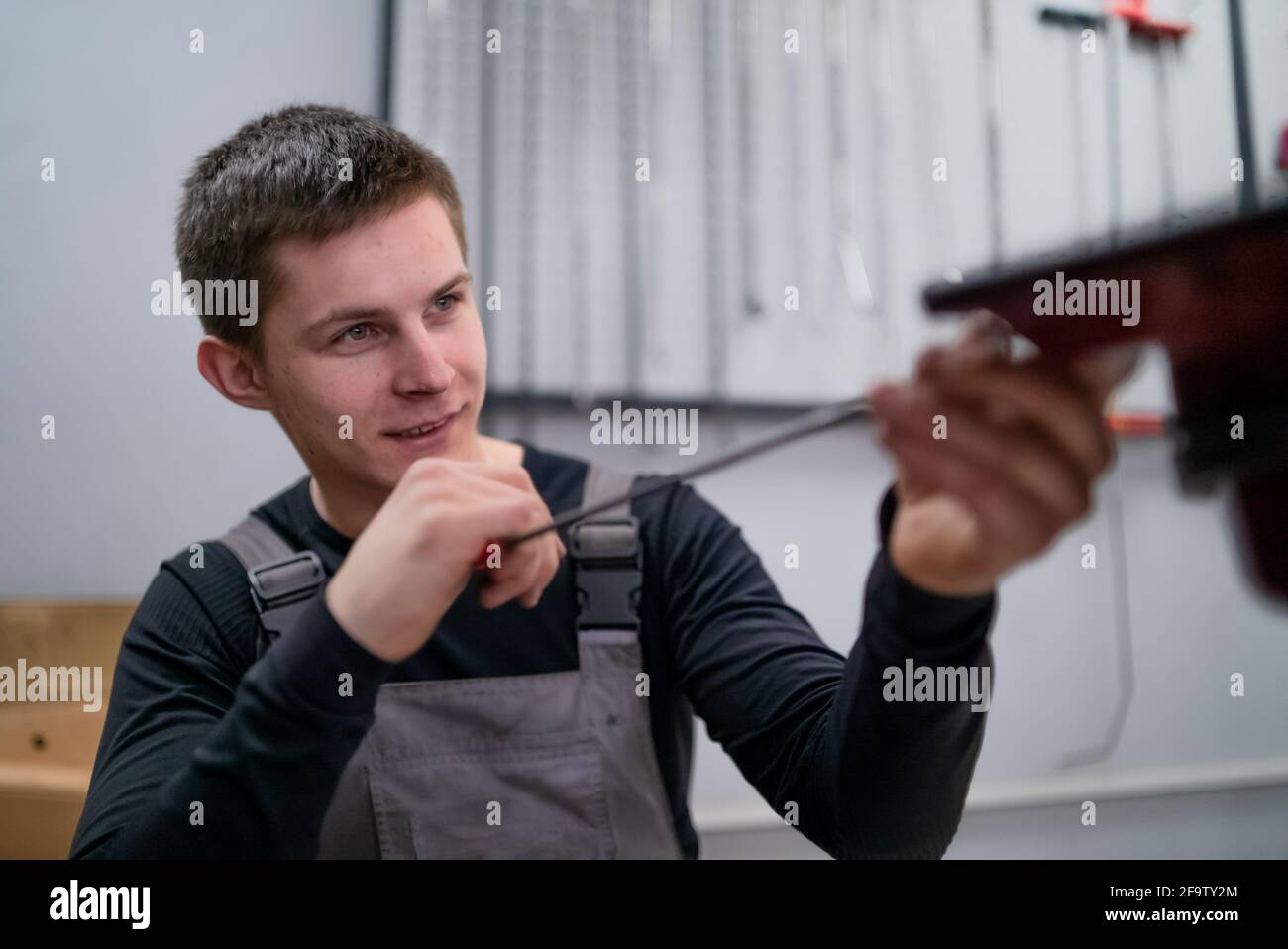 Portrait of concentrated young dent removing specialist on car repair station Stock Photo